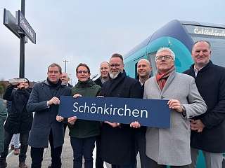 Minister Madsen und weitere mit Schönkirchen-Schild vor Akkuzug