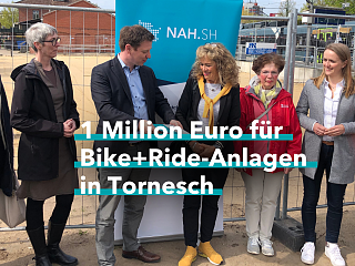 Menschengruppe vor einem Baustelle mit Bauzaun