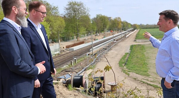 Verkehrsminister Madsen, Bürgermeister Jan Lindenau und Jochen Schulz (NAH.SH) betrachten die Baustelle für den neuen Haltepunkt in Lübeck Moisling.