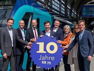 © nordbahn/ Kai Thomas Gruppe vor Zug mit 10 Jahre RB 75 Schild