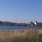 Foto von der Schleibrücke in Lindaunis, über die ein roter Zug fährt.