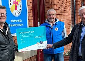 Dennis Fiedel (NAH.SH) übergibt Andreas Hainke und Gert Rathje von der Bahnhofsmission die Spende der NAH.SH-Mitarbeiter*innen