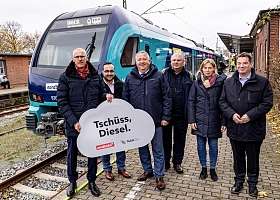 Menschengruppe vor Zug mit Tschüss, Diesel Schild