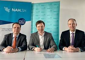 3 Menschen an einem Tisch bei der Vertragsunterschrift 