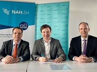 3 Menschen an einem Tisch bei der Vertragsunterschrift 