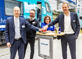 Personen an Stehtisch vor Akkuzug