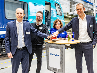 Personen an Stehtisch vor Akkuzug