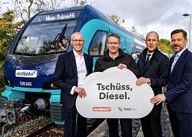 Menschengruppe vor Zug mit Tschüss Diesel Schild