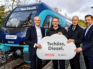 Menschengruppe vor Zug mit Tschüss Diesel Schild