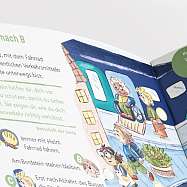 Kiki Karotte und Winni Wolle stehen an einem Zebrastreifen-Schild, man sieht eine Seite im Möhrchenheft