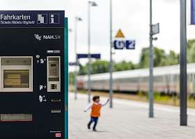 Links im Bild ist ein Farkartenautomat zu sehen und weiter hinten spielt ein Kind auf dem Bahnsteig.