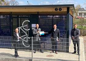 Vier Herren stehen vor einer Bike and Ride-Anlage