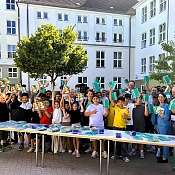 Man sieht viele Schülerinnen und Schüler mit den NAH.SH-Hausaufgabenheften.
