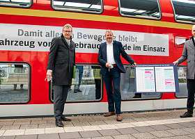 3 Herren stehen vor einem roten Zug