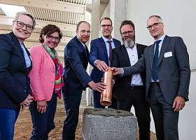 eine Zeitkapsel wird ins Fundament der Akkuzug-Werkstatt eingelassen