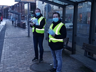 Zwei Personen verteilen medizinische Masken am Bahnhof von Flensburg