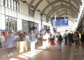 Bahnhofshalle mit Menschen und Anzeigetafel im Hintergrund