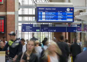 Pendler am Kieler Hbf mit einer Anzeigetafel im Hintergrund