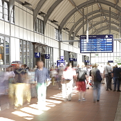 Pendler in Bahnhofshalle mit Anzeigetafel im Hintergrund 