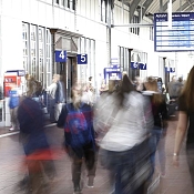 Pendler in Bahnhofshalle und Anzeigetafel im Hintergrund