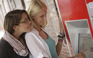 zwei Frauen stehen an einem Fahrkartenautomaten
