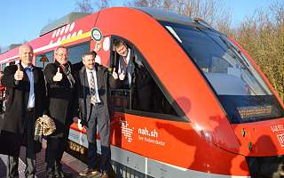 drei Personen neben Zug, die einen Daumen hoch zeigen