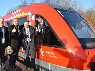 drei Personen neben Zug, die einen Daumen hoch zeigen