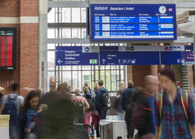 Pendler im Kieler Hbf mit Anzeigetafel im Hintergrund