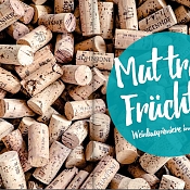 große Sammlung von Korken, rechts im Vordergrund: runder türkiser Kreis mit Schriftzug: Mut trägt Früchte