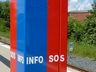 Rote und blaue Infostele mit der Aufschrift: Info und SOS auf einem Bahnsteig