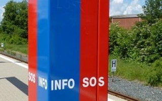 Rote und blaue Infostele mit der Aufschrift: Info und SOS auf einem Bahnsteig