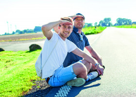 zwei Männer sitzen in der Sonne am Wegrand